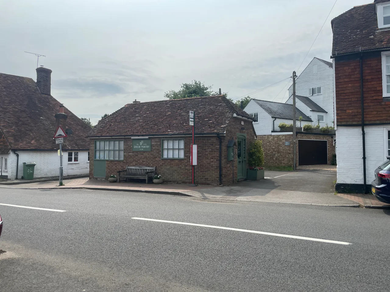 A village street scene in Lamberhurst with period weatherboard and tile-hung buildings and a roadside bench.