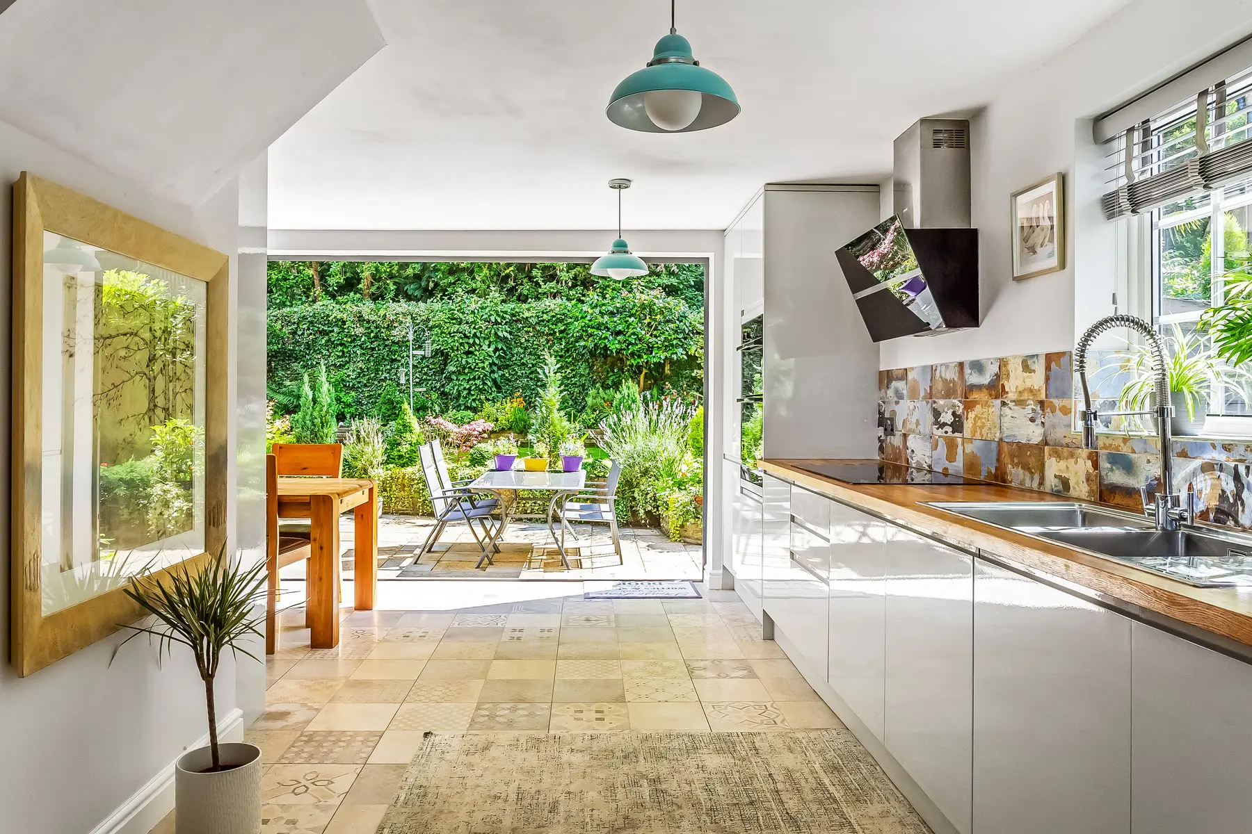 A bright contemporary kitchen with bifold doors open onto a planted Tunbridge Wells garden, photographed for a Kings Estates sale