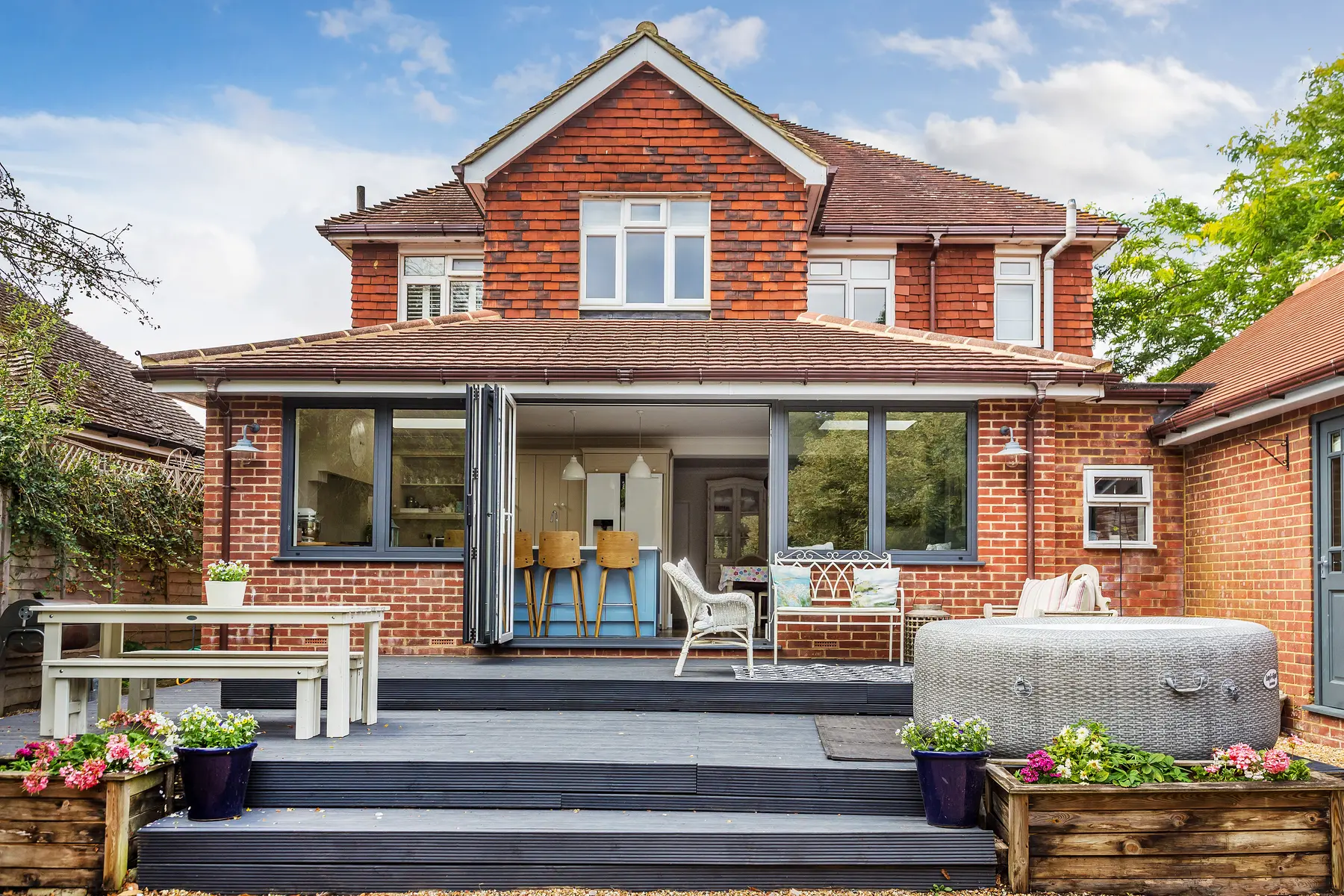 A handsome managed home with bifold doors open onto a dressed terrace and bright kitchen beyond — a Kings Estates let presented to standard