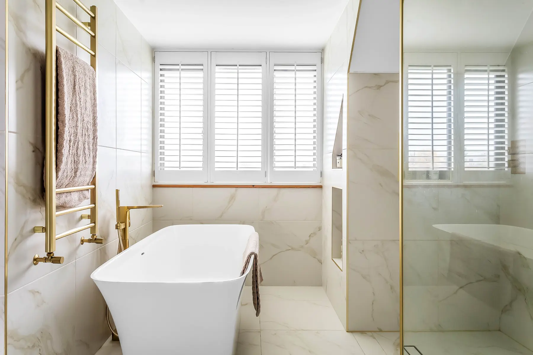 A styled marble bathroom with brushed-brass fittings and a freestanding bath, photographed for a Kings Estates sale