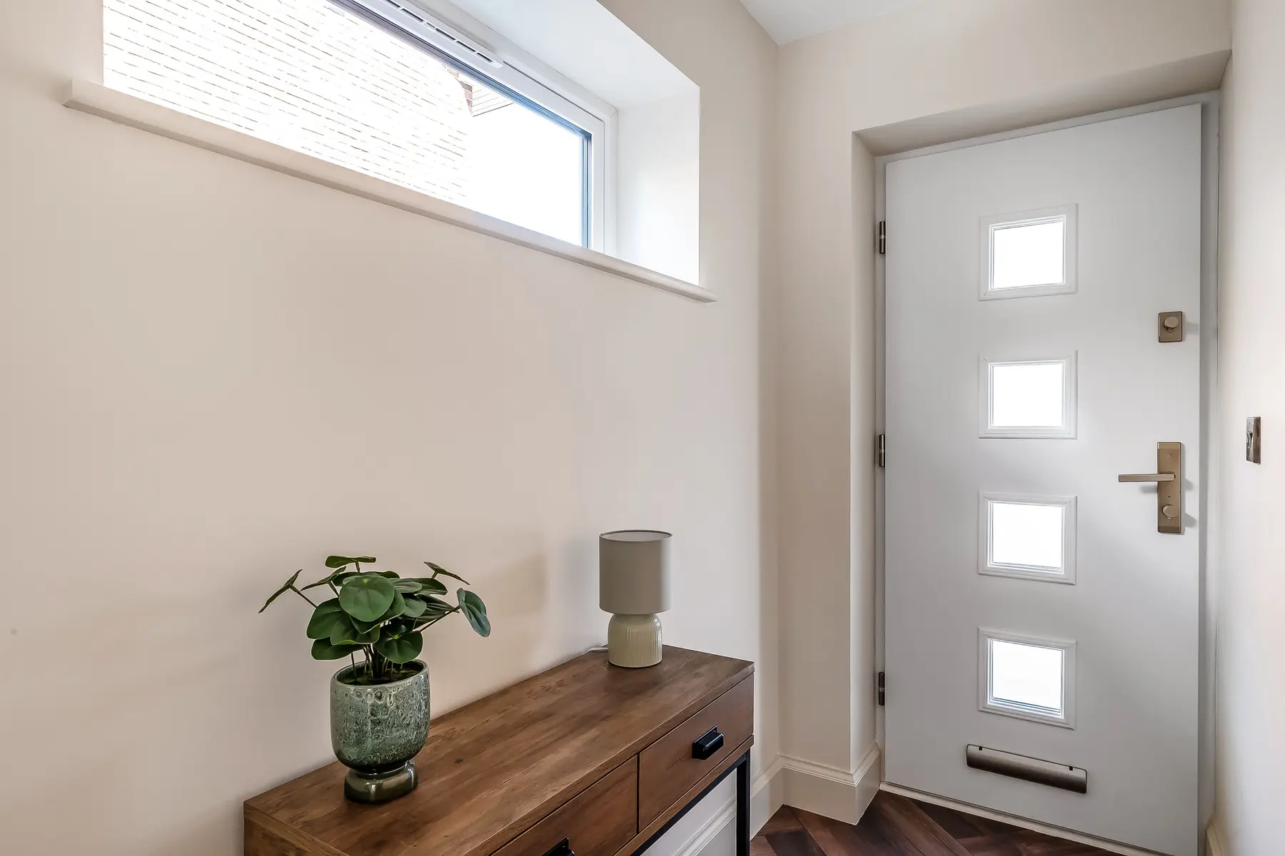 A calm entrance hall with a composite front door and warm timber console — the threshold of a new tenancy