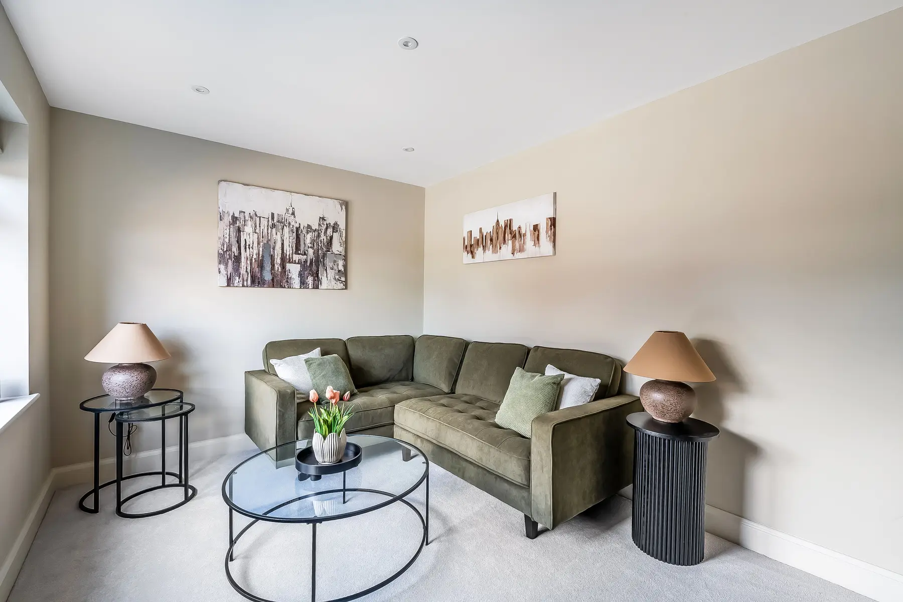 A bright, neutrally styled living room with a deep-green sofa and soft natural light — a managed Kings Estates rental