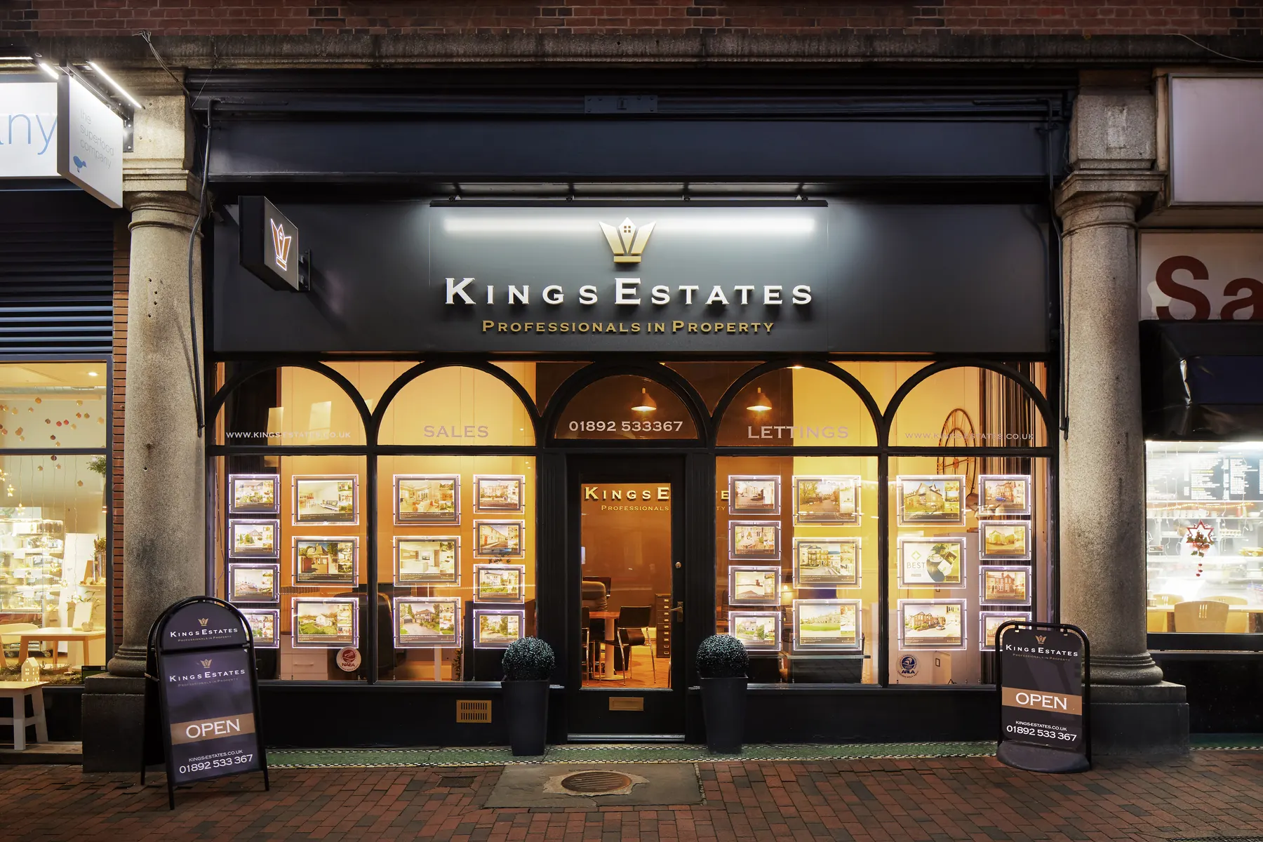 Kings Estates' Tunbridge Wells office at twilight, with sales and lettings displayed in the window